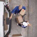 full-shot-delivery-people-holding-box | moving company in winnipeg