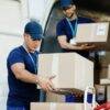 Young delivery man and his coworker unloading boxes from a van.