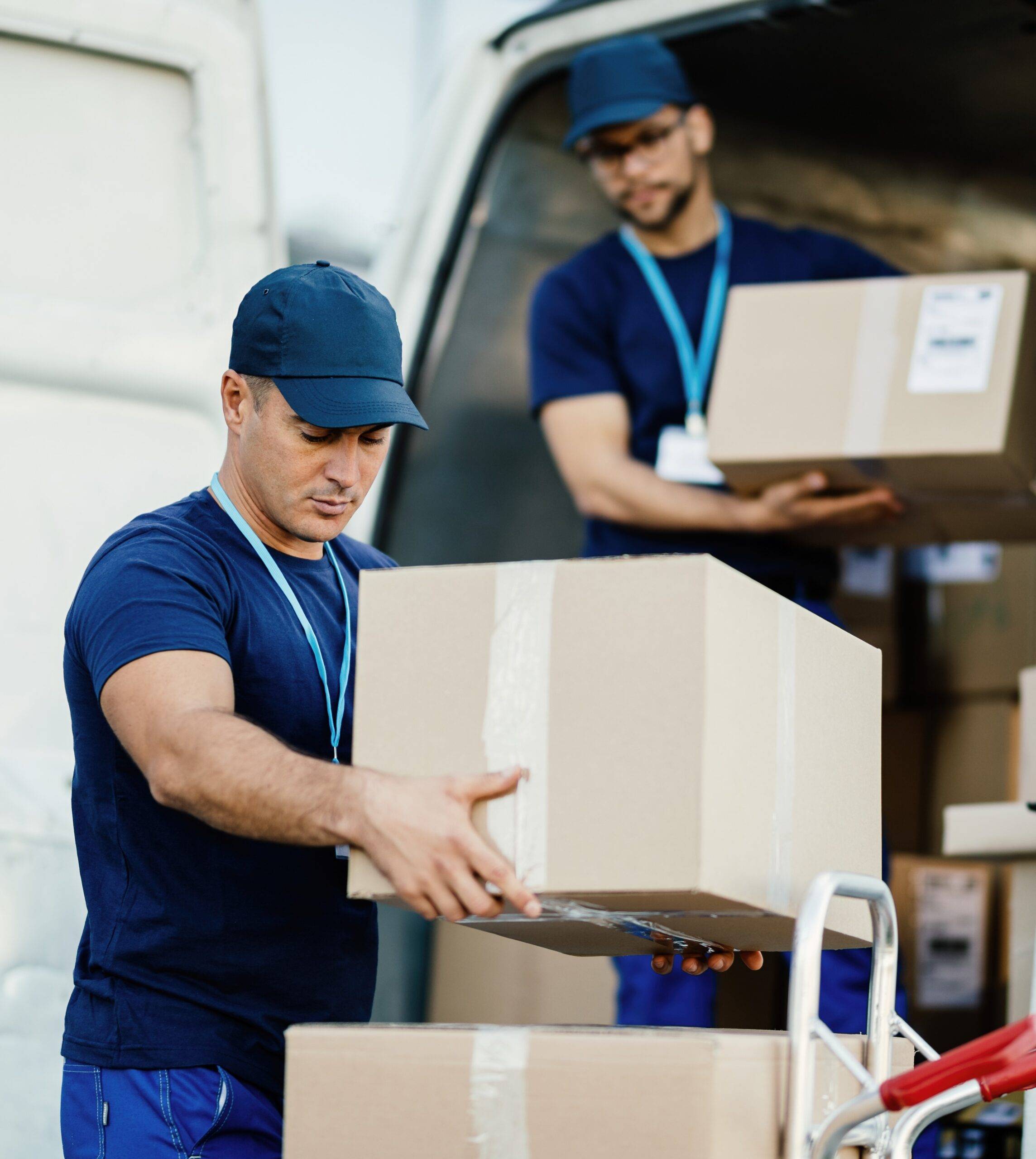 Young delivery man and his coworker unloading boxes from a van.